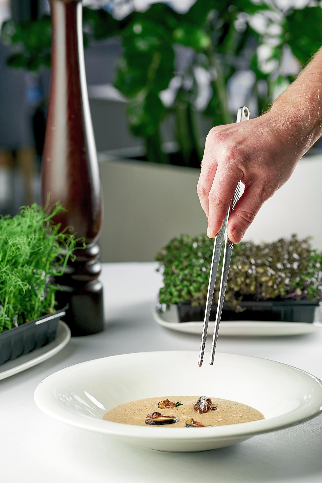 Chef demonstrating precise plating on a wooden table